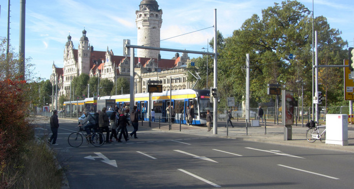 Straße und eine Straßenbahnhaltestelle mit dem Neuen Rathaus im Hintergrund