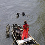 Foto eines Mannes auf einem Boot und eines Tauchers im Wasser. Auf dem Boot liegt Müll vom Grund des Flusses.