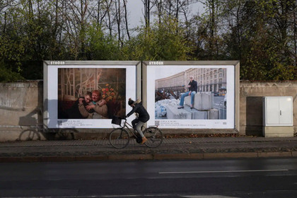 Blick auf zwei Plakatwände mit Fotomotiven aus Kiew, davor fährt ein Radfahrer