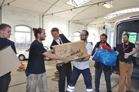 Helfer laden die ersten Kartons mit Spenden aus einem Transporter aus.