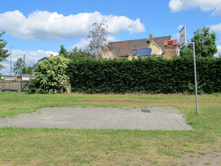 Basketballkorb an einer Freifläche vor eine Hecke und einem Wohnhaus in Lützschena