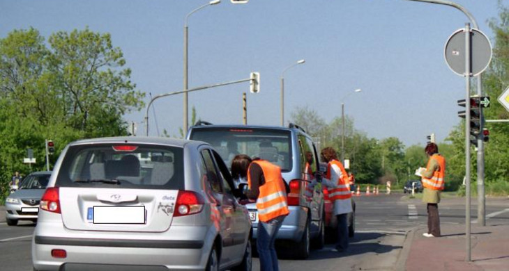 Befrager stellen Autofahrern an einer roten Ampel Fragen zu ihrer Verkehrsnutzung
