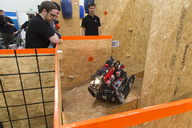 Mensch steuert Robo-Fahrzeug durch einen Parcour aus Spanplatten