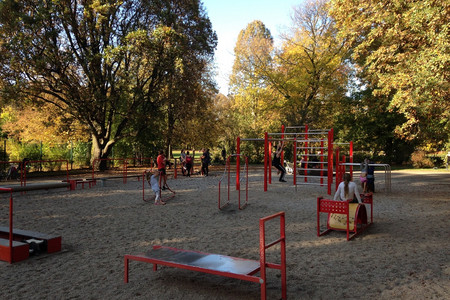 Kinder und Jugendliche turnen an verschiedenen Kletter- und Fittnessgeräten im Park herum.