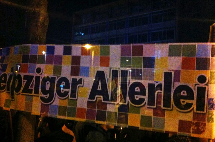 Demonstranten halten ein buntes Plakat mit der Aufschrift "Leipziger Allerlei" hoch.