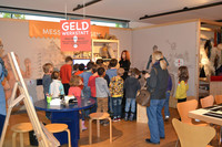 Gruppe von Kindern bei eine Führung im Kindermuseum des Stadtgeschichtlichen Museums. Eine Mitarbeiterin erklärt den Kindern etwas.