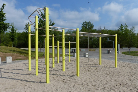 Sportanlage für Calisthenics und Fitness-Sport. Konstruktion aus Metallstangen auf einem Sandplatz, mit Klimmzugstange, Stangen zum Hangeln und weiterem