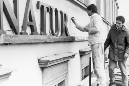 Zwei Arbeiter bringen den Schriftzug Naturkundemuseum am Gebäude an