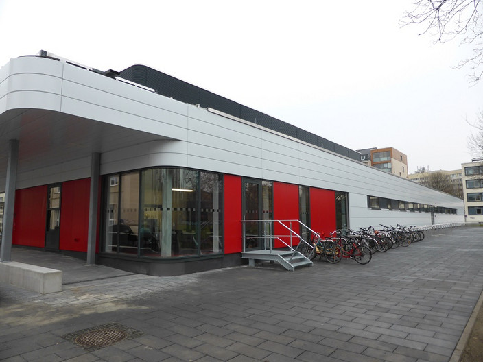 Außenansicht der Sporthalle Brüderstraße mit Pflasterweg und vor der Halle abgestellten Fahrrädern