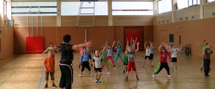 Kinder turnen mit Sportlehrerin in der Sporthalle An der Kotsche