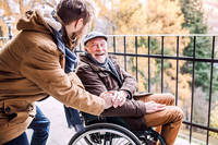 Ältere Mann im Rollstuhl ist mit seinem Sohn unterwegs