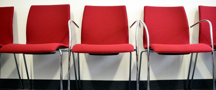 Eine Stuhlreihe mit roten Stühlen in einem Warteraum
