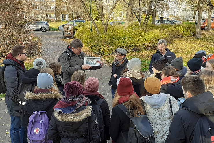 Eine Gruppe Menschen steht im Freien, ein mann erklärt etwas anhand einer Karte.