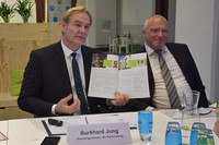 Oberbürgermeister Burkhard Jung sitzt an einem Tisch, hält das Arbeitsprogramm aufgeschlagen in der Hand. Neben ihm sitzt Thorsten Rupp.
