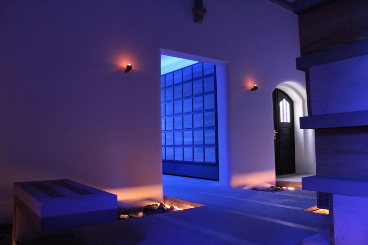 Ein blau beleuchteter Raum mit mehreren Urnenkammern aus Holz und Stein