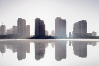 Hochhäuser der chinesischen Stadt Ordos spiegeln sich vor einem See in gespenstischer Atmosphäre.
