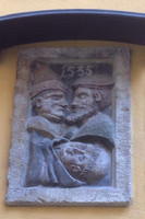 Relief mit drei menschlichen Figuren an einer Hauswand