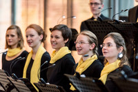 Fünf Frauen des Kammerchores der Schola Cantorum bei einem Konzert. Alle tragen gelbe Schals.