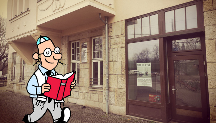 Eine männliche Cartoonfigur in typisch jüdischer Aufmachung liest ein Buch während sie am Capa-Haus vorbeiläuft