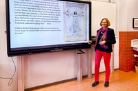 Schulleiterin Dr. Kathrin Mayer steht neben einer interaktiven Tafel