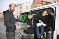 Drei Streetworker geben einen Schlafsack und Tee aus dem Hilfebus aus