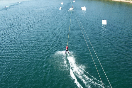 Wasserskifahrer wird an einer Seilzuganlage auf dem Wasser langgezogen