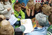 Kinder und Erwachsene schauen in ein Buch