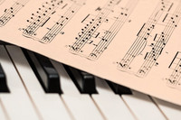 Notenblatt liegt auf Klavier-Tastatur 