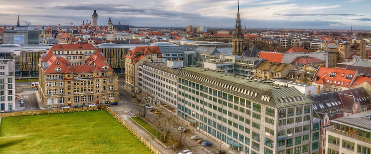 Blick über Leipzigs Stadtzentrum mit unbebauter Rasenfläche im Vordergrund