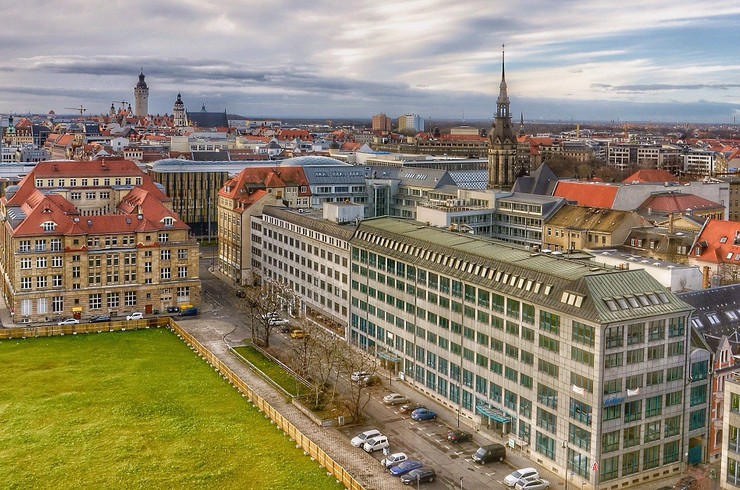 Blick über Leipzigs Stadtzentrum mit unbebauter Rasenfläche im Vordergrund