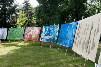 Galerie mit großformatigen Bildern auf Staffeleien im Freien