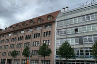 Altes Bürohaus mit Steinfassade und neues Bürohaus aus Glas und Stahl nebeneinander