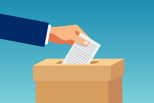 Eine Hand steckte einen Zettel in einen Wahlurne