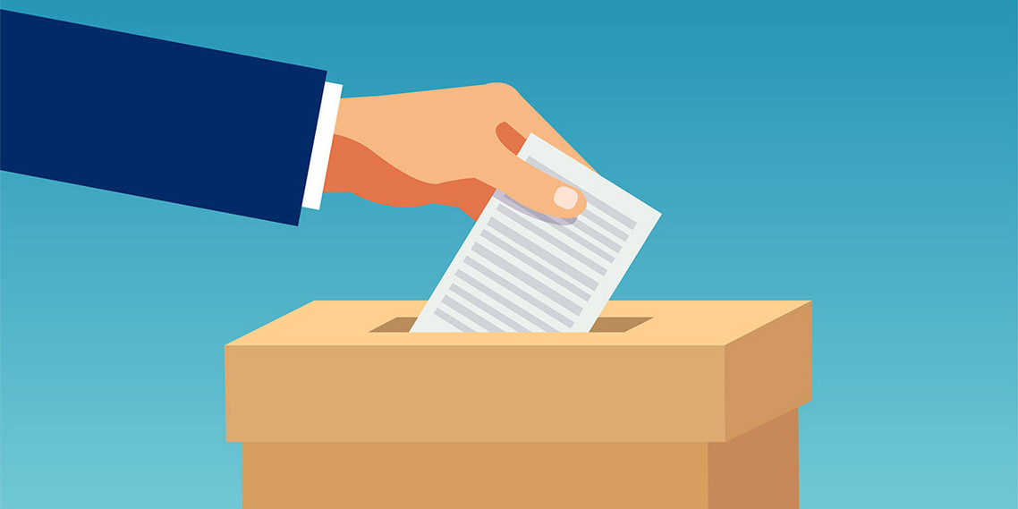 Eine Hand steckte einen Zettel in einen Wahlurne