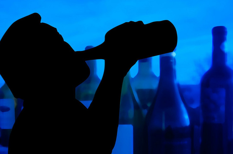 Silhouette eines trinkenden Mannes vor vielen leeren Flaschen