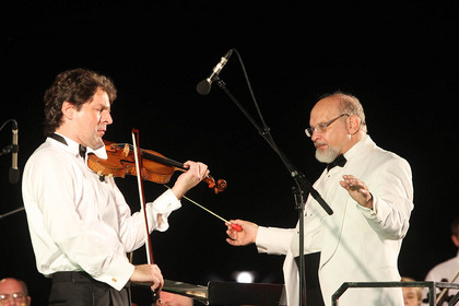 Ein Musiker spielt Violine, daneben steht Dirigent Harvey Bordovitz