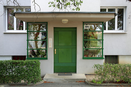 Hauseingang mit grüner Tür und Wintergarten
