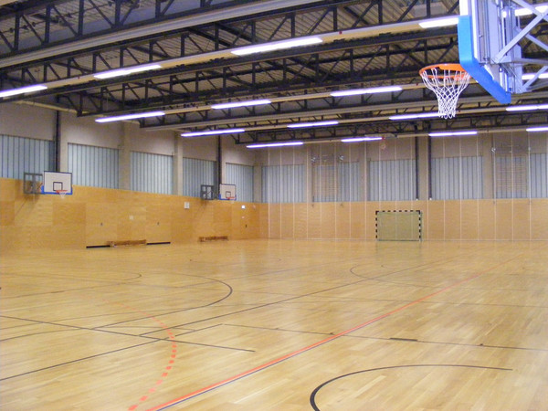 Sporthalle Radrennbahn Innenansicht mit mehreren Basketballkörben an den Wänden.