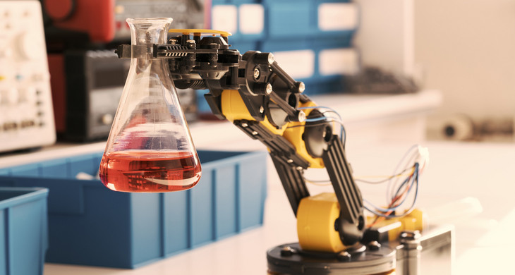 Ein Roboterarm hält einen Erlenmeyerkolben mit roter Flüssigkeit.