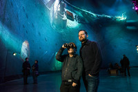 Im Asisi Panometer steht ein Vater mit seinem Sohn. Der Sohn hält ein Fernglas an die Augen. Hinter ihnen ist ein Teil des Panoramabildes mit dem Wrack der Titanic zu sehen.