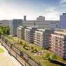Computergrafik von fünf mehrstöckigen Häusern neben einen Grünstreifen und einer S-Bahn-Linie. Im Hintergrund steht das City-Hochhaus.