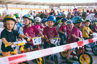 Viele kleine Kinder mit Fahrradhelmen am Start des Kindernachtrennens