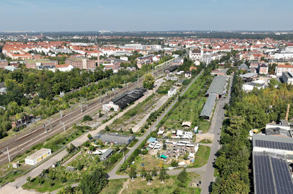 Das Gebiet des Grünen Bahnhofs Plagwitz aus der Luft. Zwischen Wohngebäuden und Industriegebäuden sind die Flächen ehemaliger Gleisanlagen sichtbar, die teilweise begrünt sind.