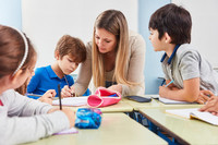 Eine Lehrerin gibt Kindern, die am Tisch sitzen, Nachhilfeunterricht.