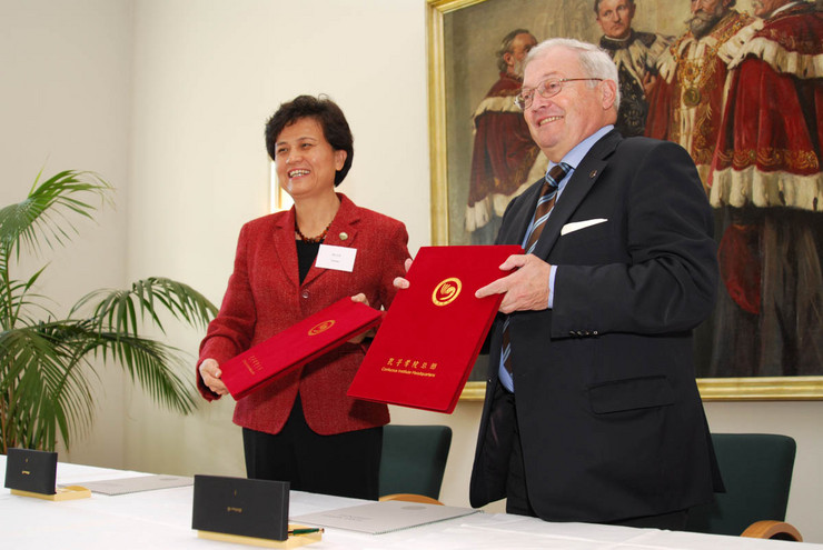 Frau Xu und Prof. Häuser halten gemeinsam ein rotes Mäppchen mit dem unterzeichneten Kooperationsvertrag in den Händen.
