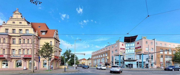 Auf dem Bild ist das Mockauer Zentrum zu sehen, in der Mitte eine Straßenkreuzung, links eine Apotheke, rechts ein Einkaufszentrum