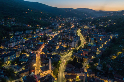Vogelperspektive auf Travnik bei Nacht mit hell erleuchteten Straßenzügen