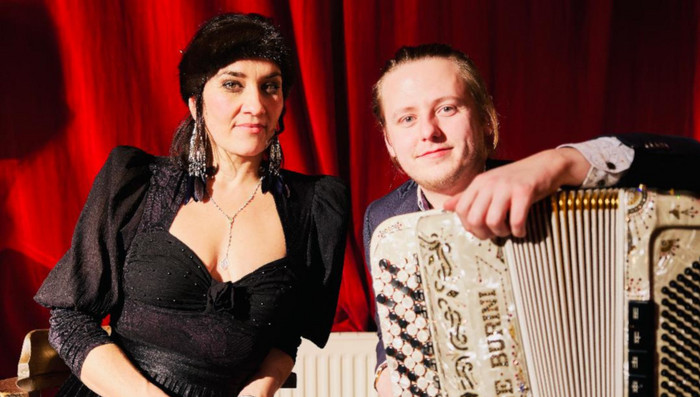 Karolina Trybala und Tadeusz Dudek mit einem Akkordeon vor einem Vorhang