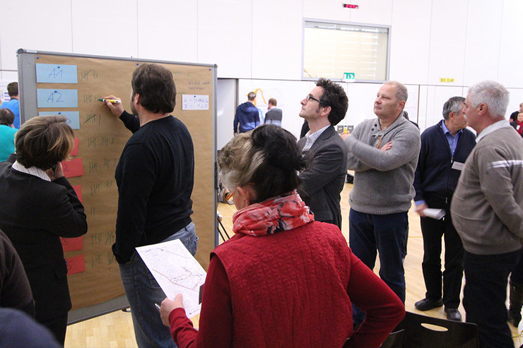 Teilnehmer eines Workshop schauen und schreiben an eine Tafel. Thema ist die Straßenbahnerweiterung in Probstheida.