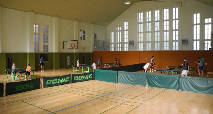 Sporthalle Breitschuhstraße in der mehrere Kinder und Jugendliche Tischtennis an mehreren Tischen spielen.